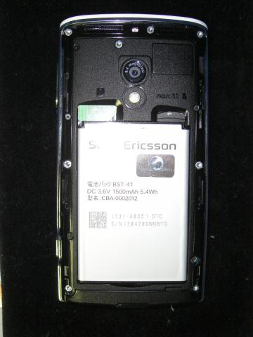 裏面；裏蓋を取りはずしたところ。かなり大きな電池が付いている。電池の左上に見える緑のものがフォーマカード。右上に見えるのがマイクロSDカード。なんと16GBのカードがおまけで付いている。(^_^)
上部中央がカメラのレンズ。